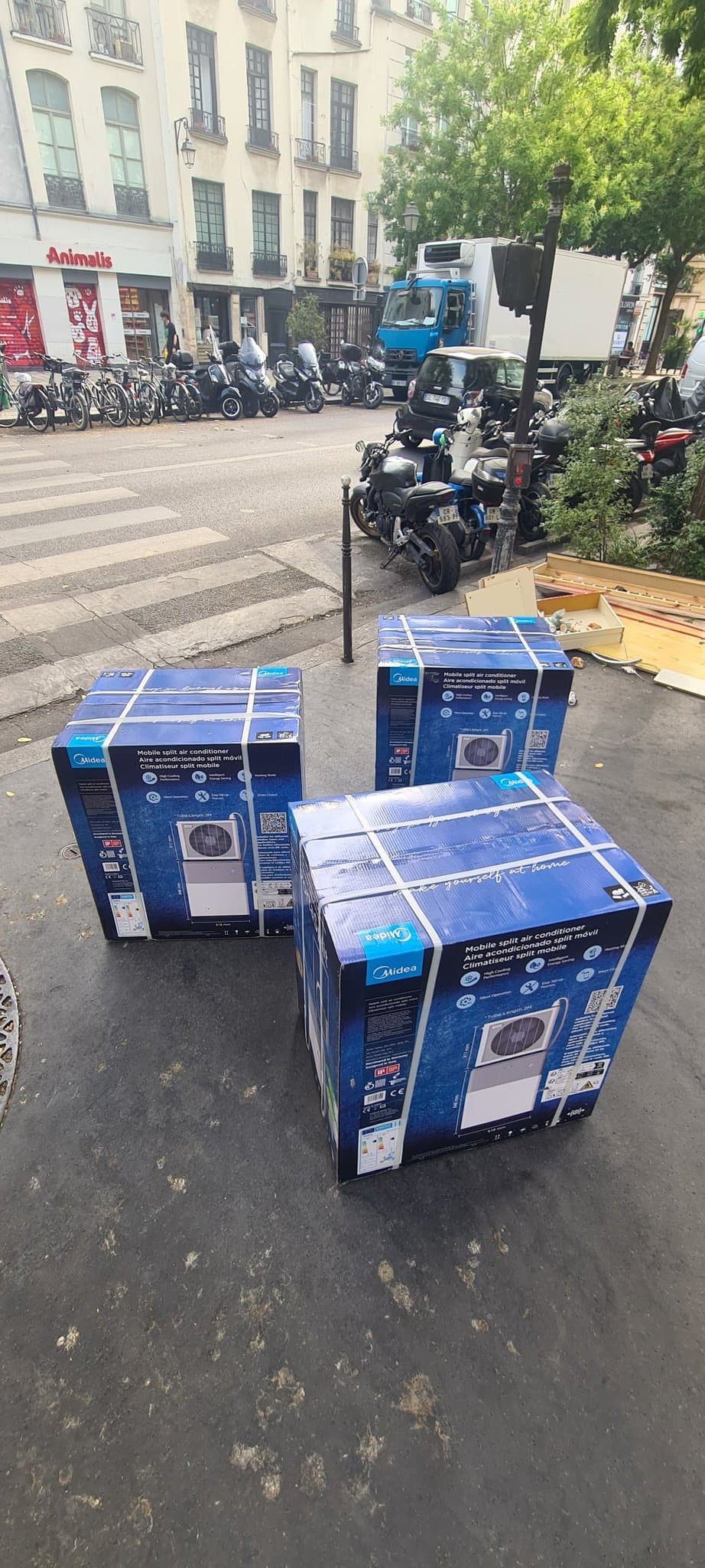 Trois cartons Midea PortaSplit livrés sur un trottoir parisien