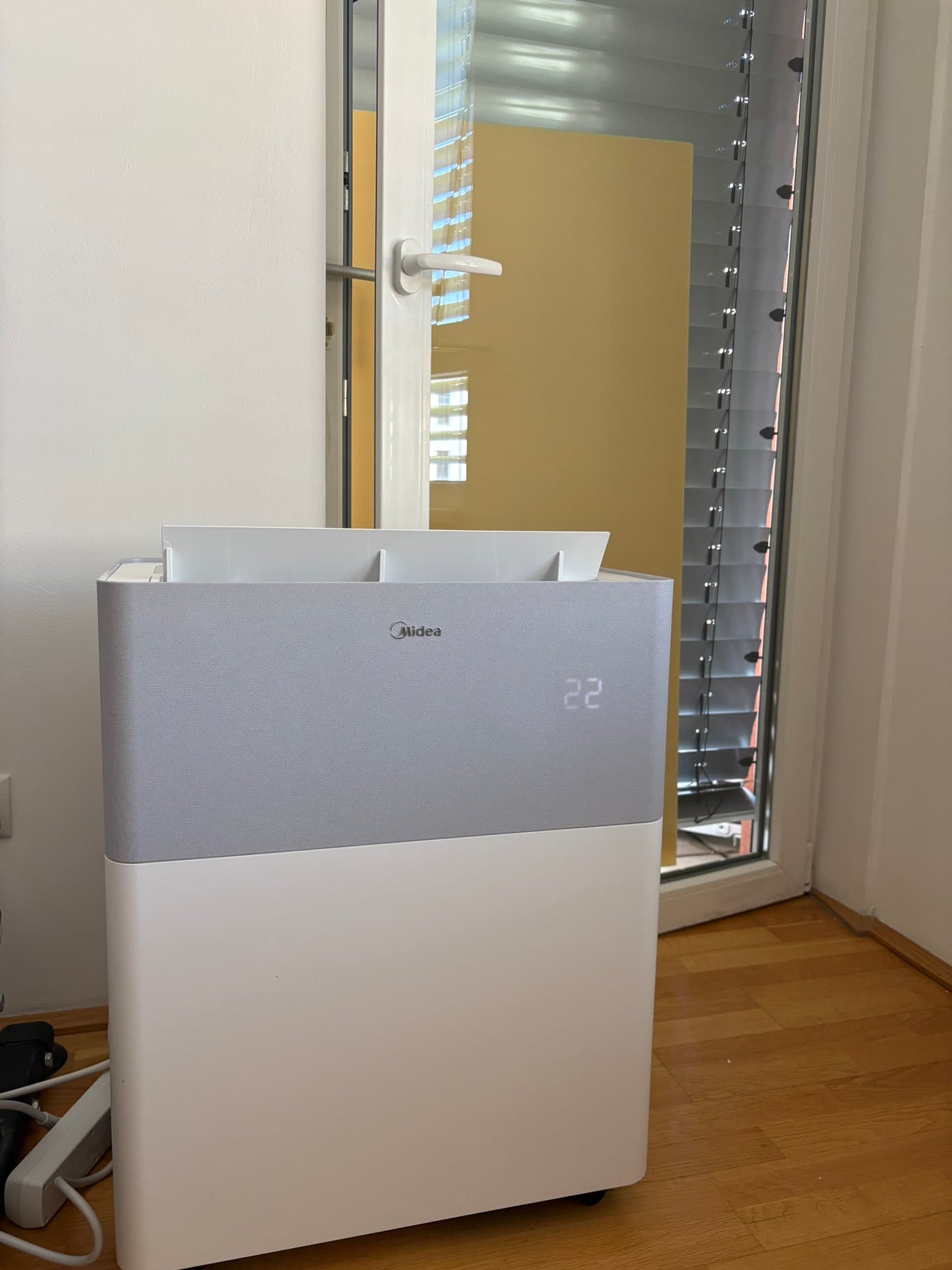 Midea PortaSplit installée devant une baie vitrée, afficheur sur 22 degrés
